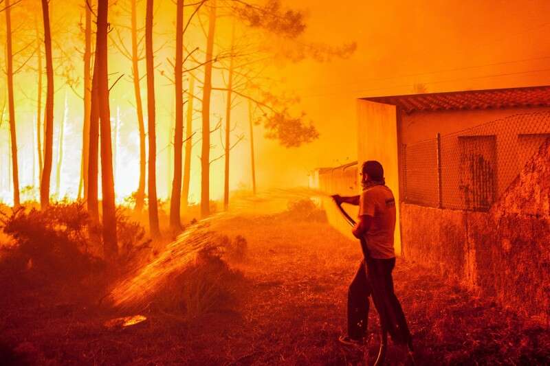 תושב מנסה להגן על ביתו מהשריפה בפורטוגל // צילום: רויטרס