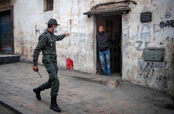 שוטר מנחה אדם להיכנס לביתו במרוקו // צילום: אי.אף.פי