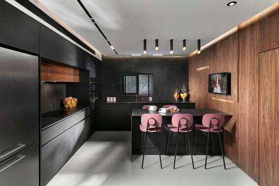  קירות המטבח ובאי מחופים דקטון מבית קוסנטינו, יחד עם חזיתות הארון הכהות יוצרים רקע שעליו מתבלטים כסאות בעלי מושב ומשענת ורודים. עיצוב אילנה וייסברג //צילום: אלעד גונן