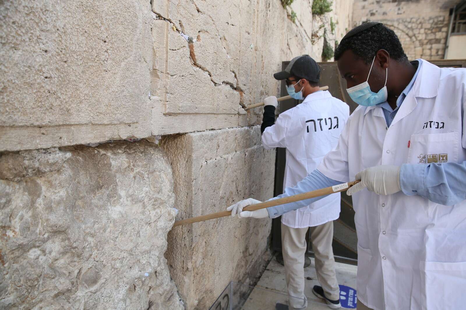 מפנים את הפתקים // צילום: הקרן למורשת הכותל המערבי // מפנים את הפתקים ,