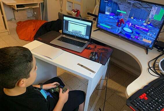 עין אחת לומדת,  עין שנייה משחקת. רותם (9) בשיעור בזום // צילום: עמי שומן