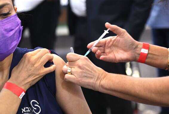 עובדת במרכז הרפואי שיבא תל השומר מתחסנת לקורונה // צילום: גדעון מרקוביץ'