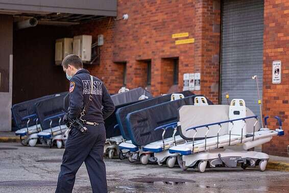 שוטר שומר על מיטות להובלת חולים בניו יורק // צילום: רויטרס