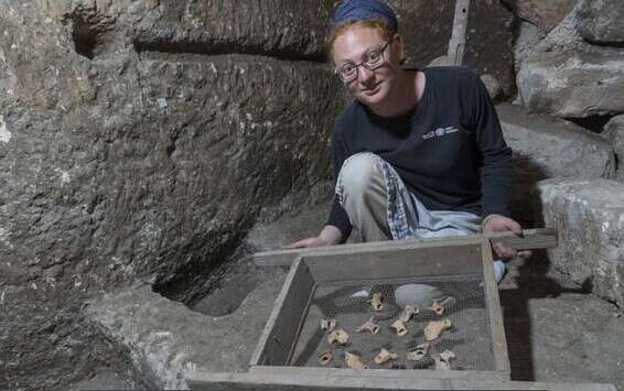 תהילה שדיאל, מנהלת החפירה, עם שברי נרות חרס מתקופת בית שני שנחשפו בתוך המערכת התת קרקעית // צילום: שי הלוי, רשות העתיקות