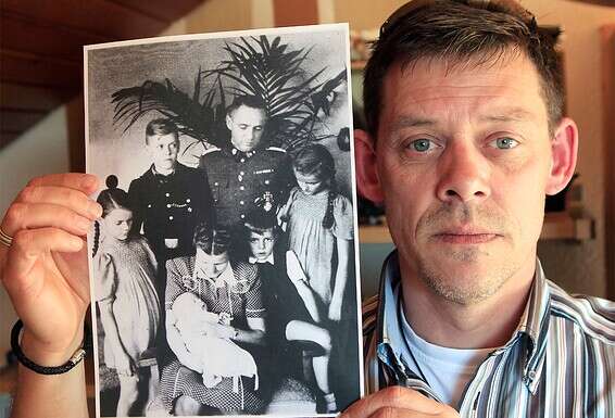 ריינר הס ב־2011, עם תמונת סבו, רודולף הס,  וילדיו בשנות ה־30. "הוא משחק בכולם  בשקרים, הוא מניפולטור", אומר קאי  // צילום: AP