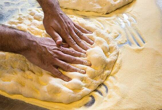 לישת הבצק. בכל יום מכינים את הביגה, בצק מקדים שמשמש בסיס לפיצות של מחר // צילום: איתיאל ציון