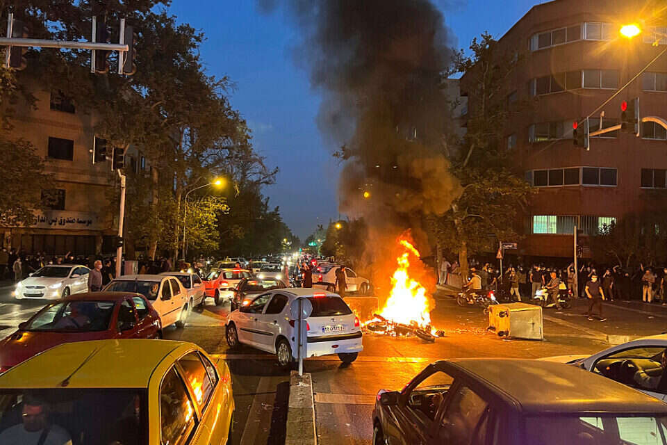 אופנוע משטרתי עולה באש במהלך ההפגנות באיראן , אי.פי