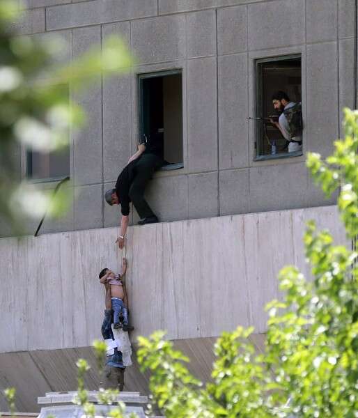 ילד מפונה מהמבנה בשעה שחמוש מביט בו מהחלון // צילום: סוכנויות הידיעות