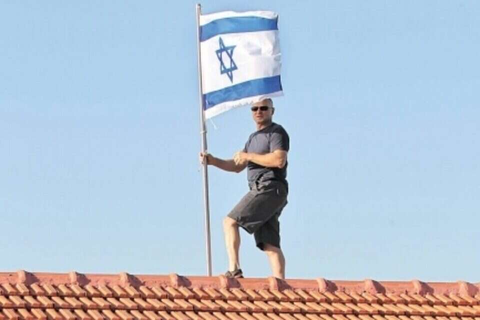 צילום: מישל דוט קום // נועם שליט מחזיר את דגל ישראל לגג ביתו במצפה הילה, אתמול ,
