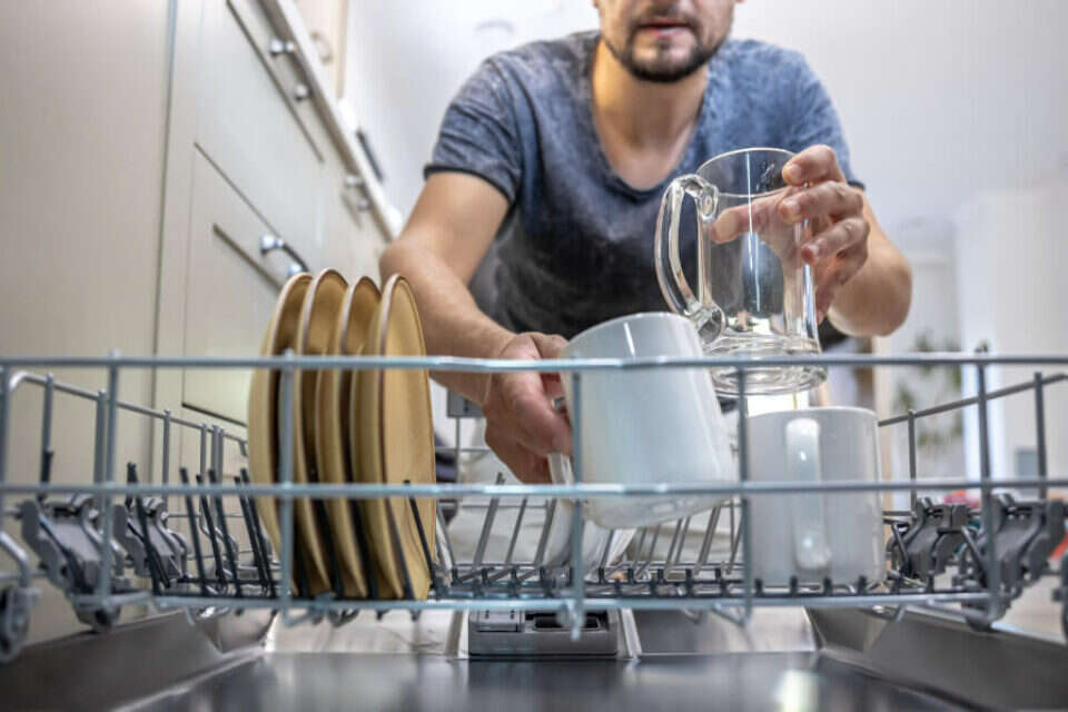 גבר מוציא כלים ממדיח כלים