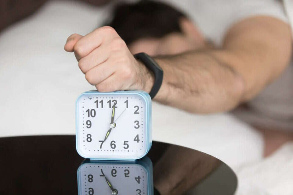 בחור לוחץ על כפתור הנודניק בשעון המעורר