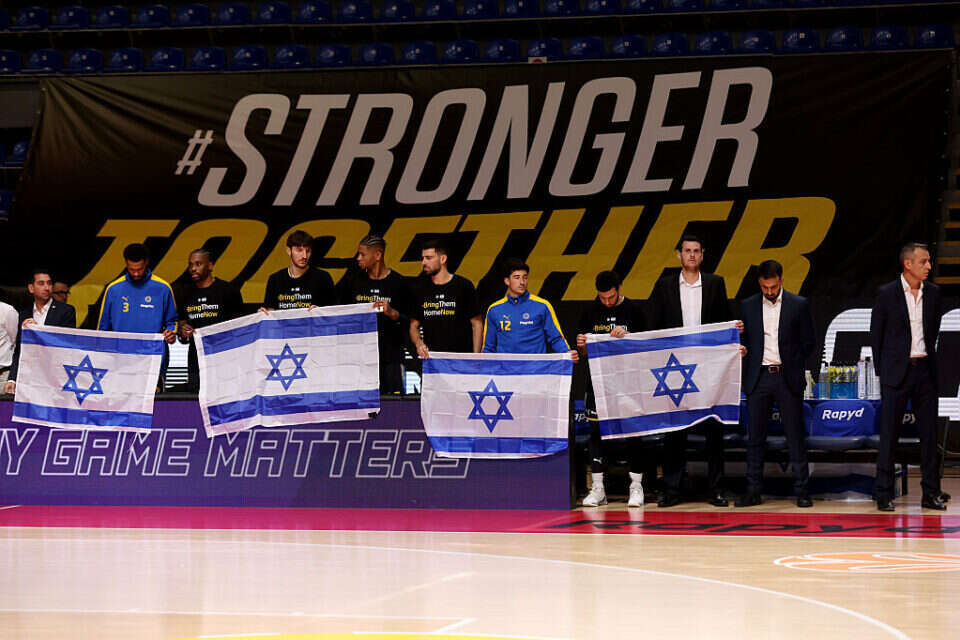 שחקני מכבי עם דגלי ישראל, אתמול לפני השריקה. לא נשברים , EPA