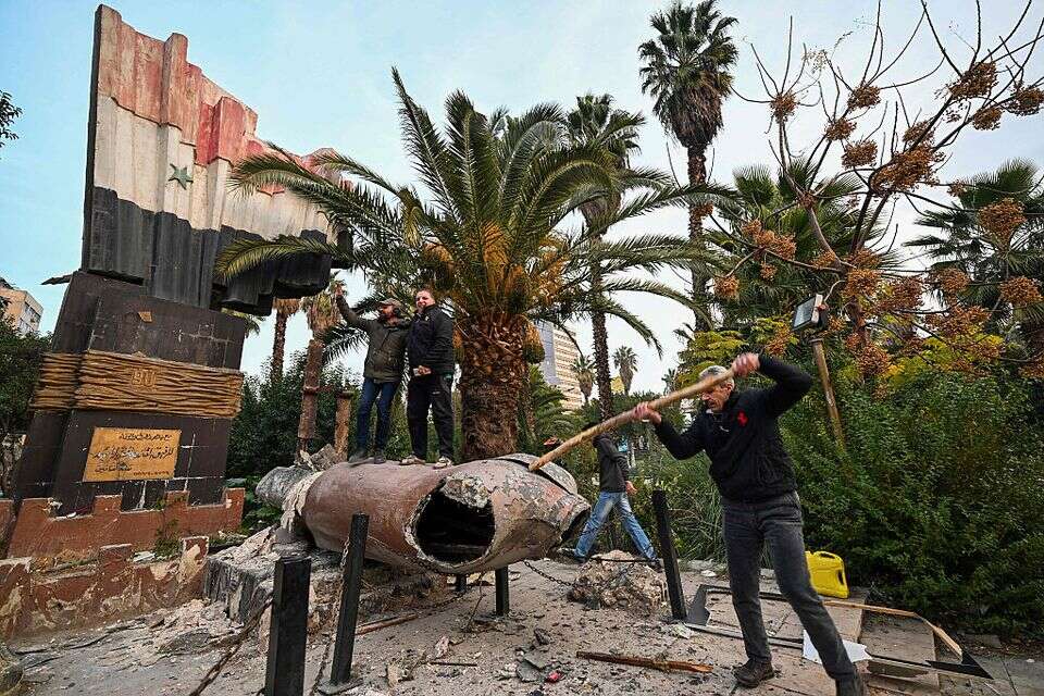 אנשים עומדים על פסל שהופל של נשיא סוריה המנוח חאפז אל-אסד בדמשק , AFP