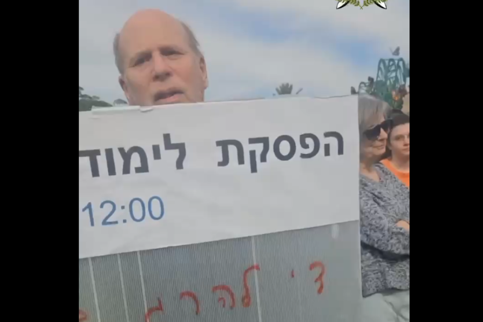 פרופ' רפאל גרינברג מניף שלט במהלך ההפגנה באוניברסיטת ת"א , אם תרצו