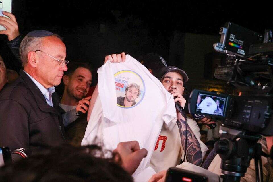 אלי-ה כהן מניף חולצה של אלון אהל בשעה שנואם במועצה בה גר , אורן בן חקון