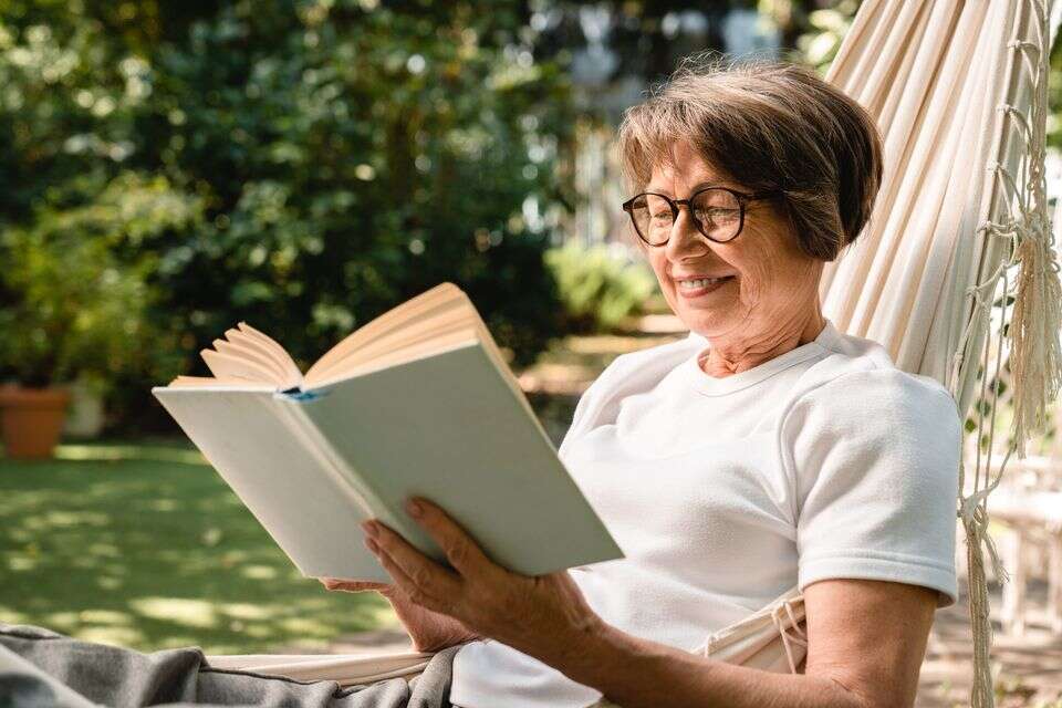 אישה בגיל השלישי קוראת ספר להנאתה , istockphoto