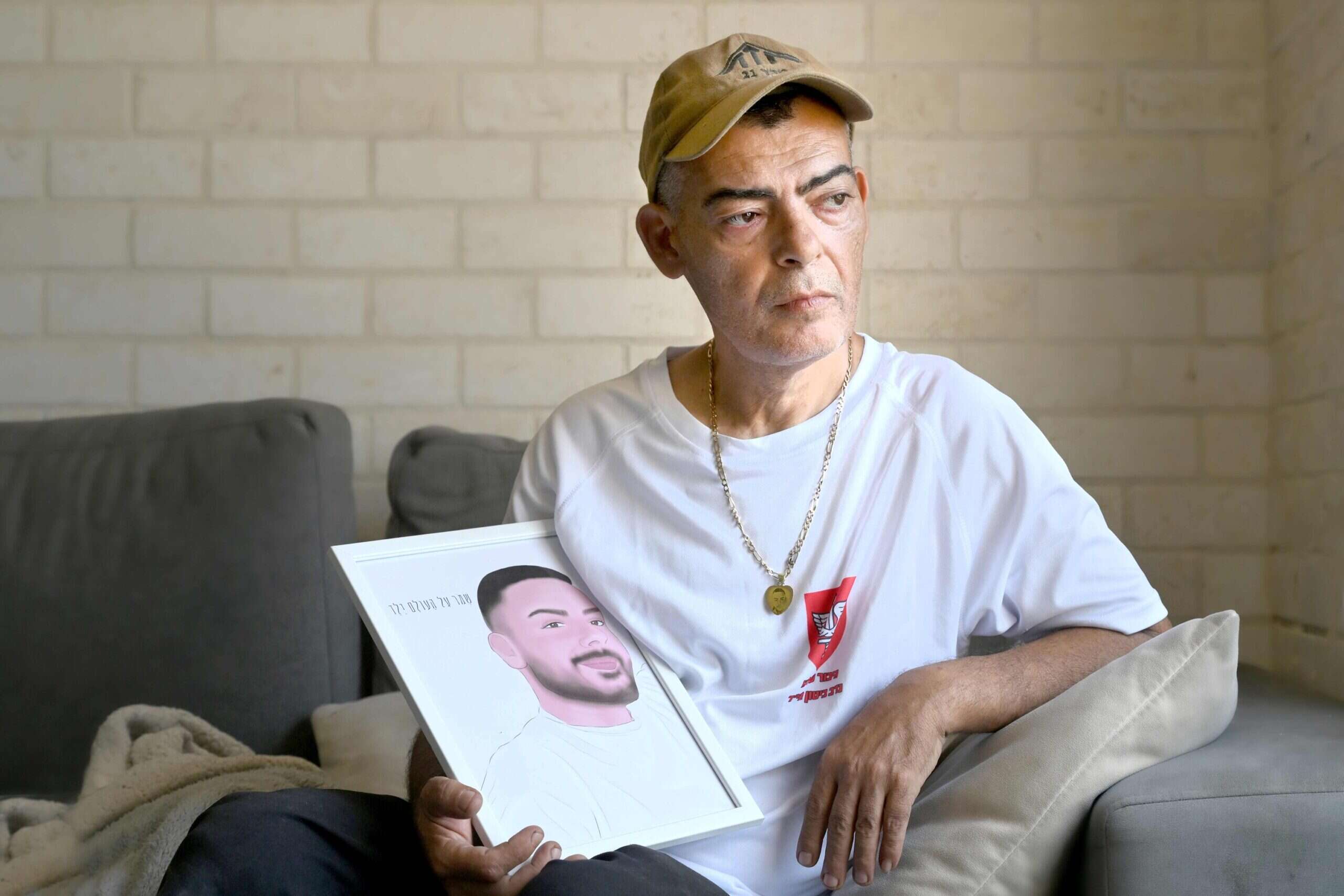 מוטי עם תמונת בנו. "הוא הספיק לי להגיד לי בטלפון: 'אבא, תוציא את הנשק שלי ותירה בכל מחבל שיתקרב לבית" , אפרת אשל