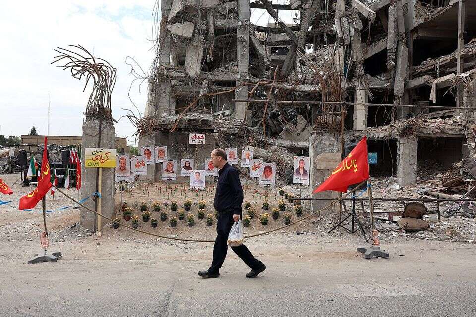 אזרח בטהרן חולף על פני מבנה שנהרס במלחמה , אי.פי.איי