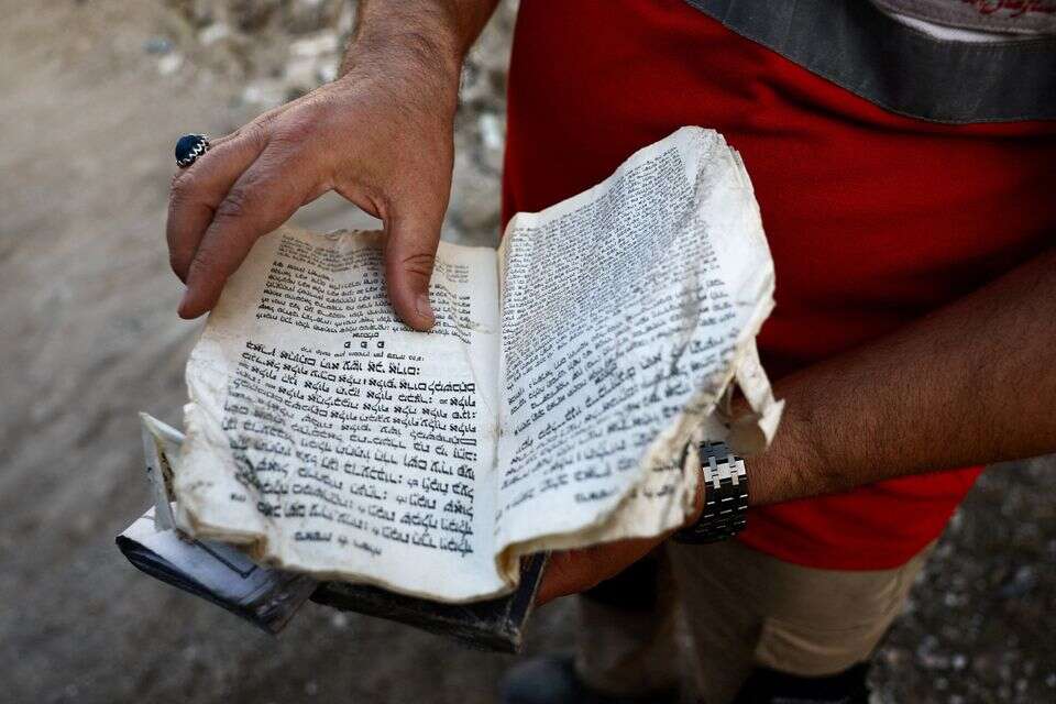 חבר בסהר האדום האיראני מחזיק את התורה בבית כנסת שניזוק בתקיפה , רויטרס