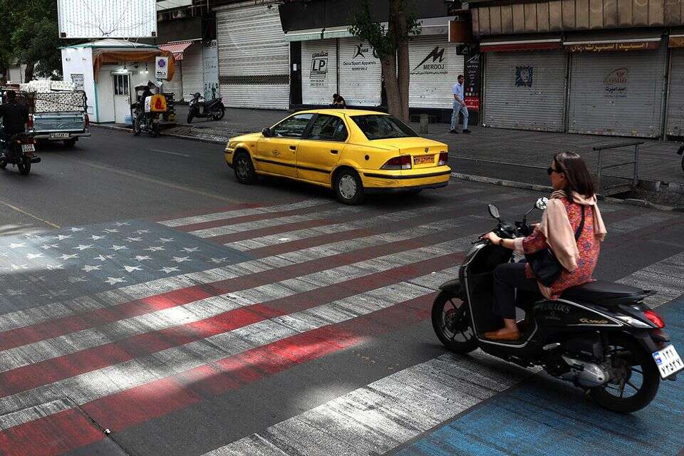 כלי רכב באיראן נוסעים על כביש שצבוע בדגלי ישראל וארה"ב , AFP