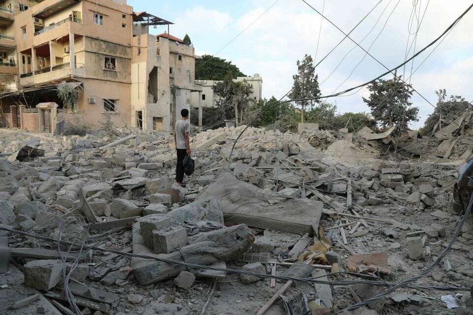 אדם עומד בתוך הריסות בית בלבנון לאחר תקיפה של צה"ל , AFP