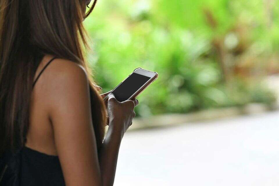 אשה מביטה במסך הטלפון הנייד שלה , גטי אימג'ס
