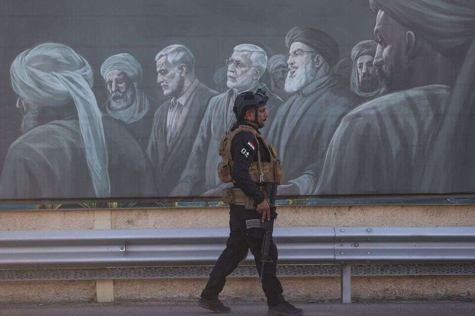 חייל של הכוחות המיוחדים בעיראק חולף על פני ציור קיר של נסראללה ובכירים איראנים שנהרגו , AFP