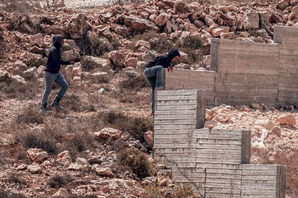 מתיישבים מנסים לקפוץ מעל הגדר של בית בכפר קוסרא , AFP
