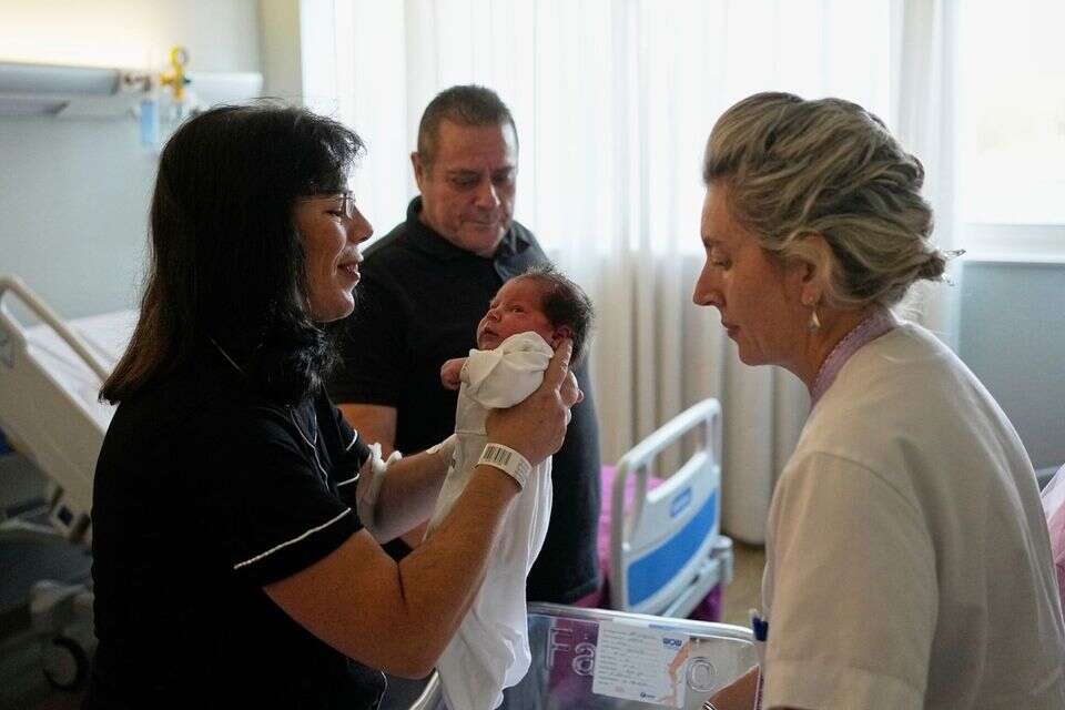 כריסטינה ראפטי-צלפי אוחזת בבתה ג'ורג'יה, בעוד בעלה קונסטנטינוס ראפטיס מתבונן בהן , AP