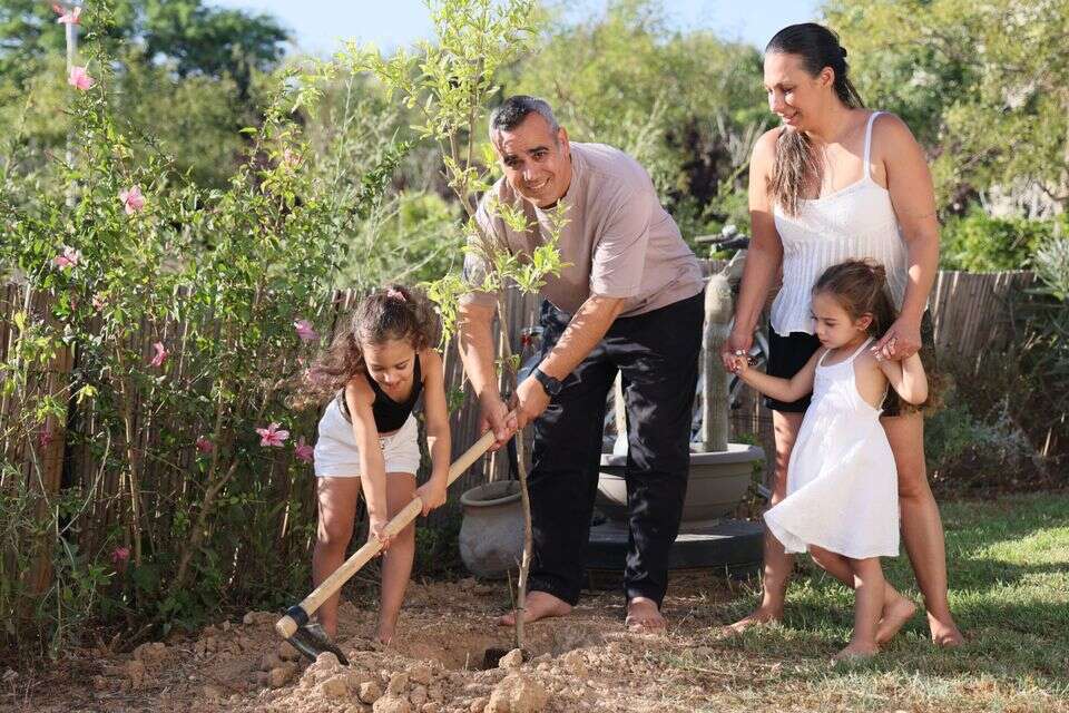עמרי מירן ולישי מירן-לביא נוטעים עץ רימון עם בנותיהם בחצר הבית בכרמית , יהונתן שאול
